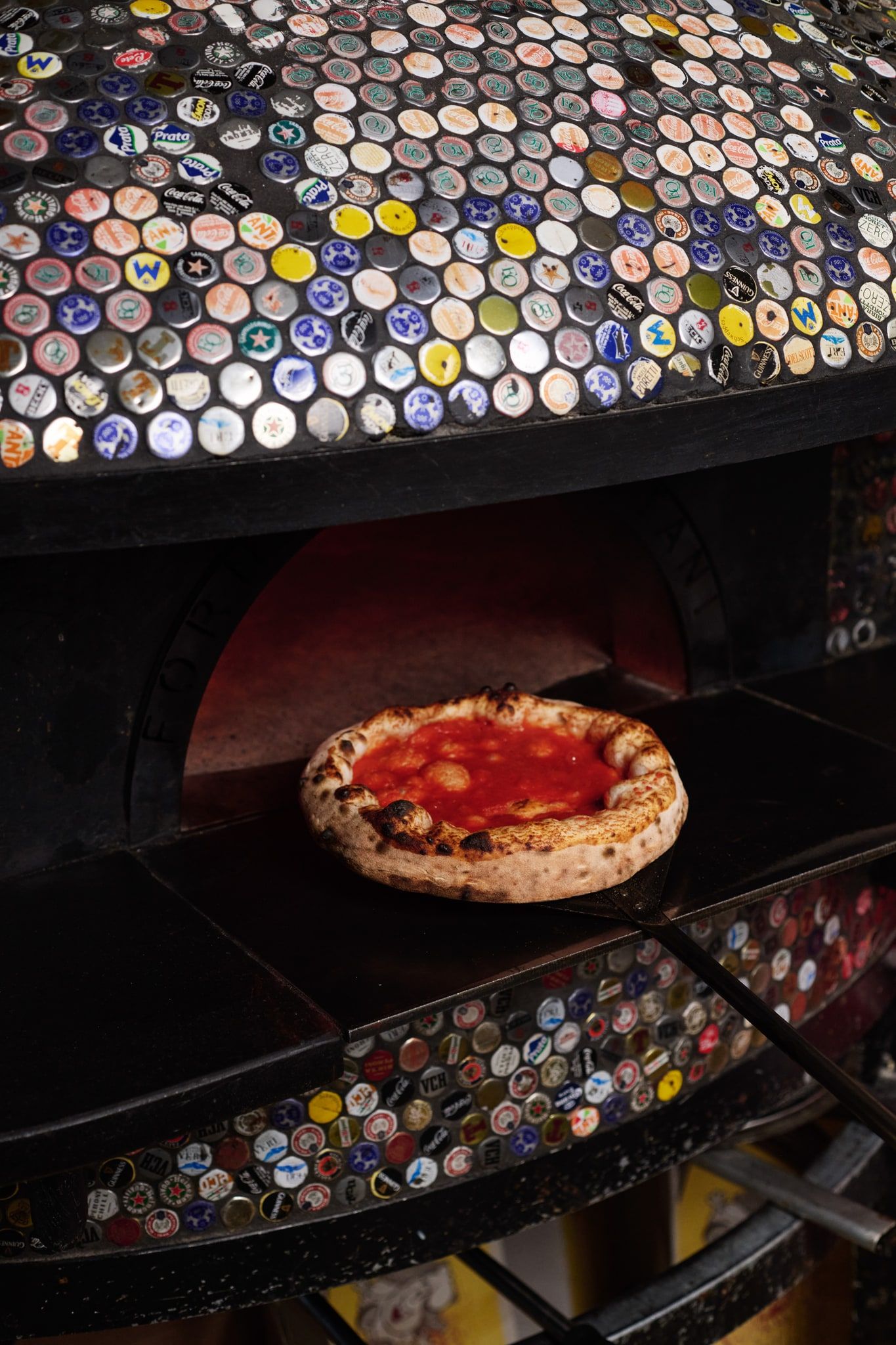 Una marinara nel forno a legna, sotto la cupola rivestita di tappi di bottiglia