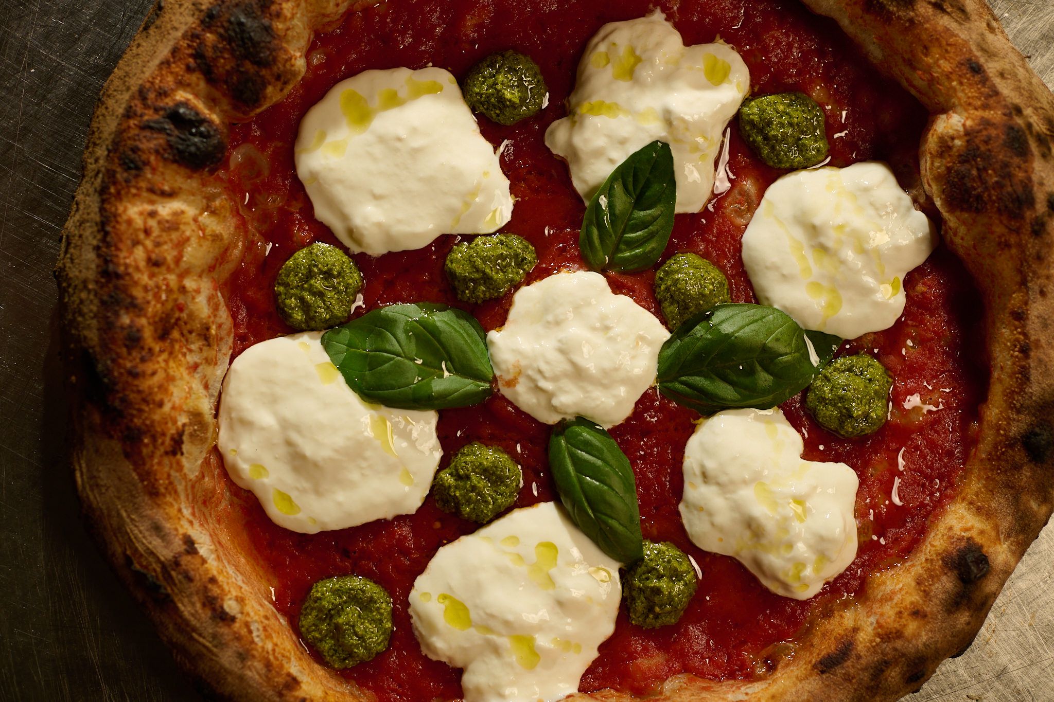 Pizza con stracciatella, pesto di basilico e foglie di basilico, vista dall’alto