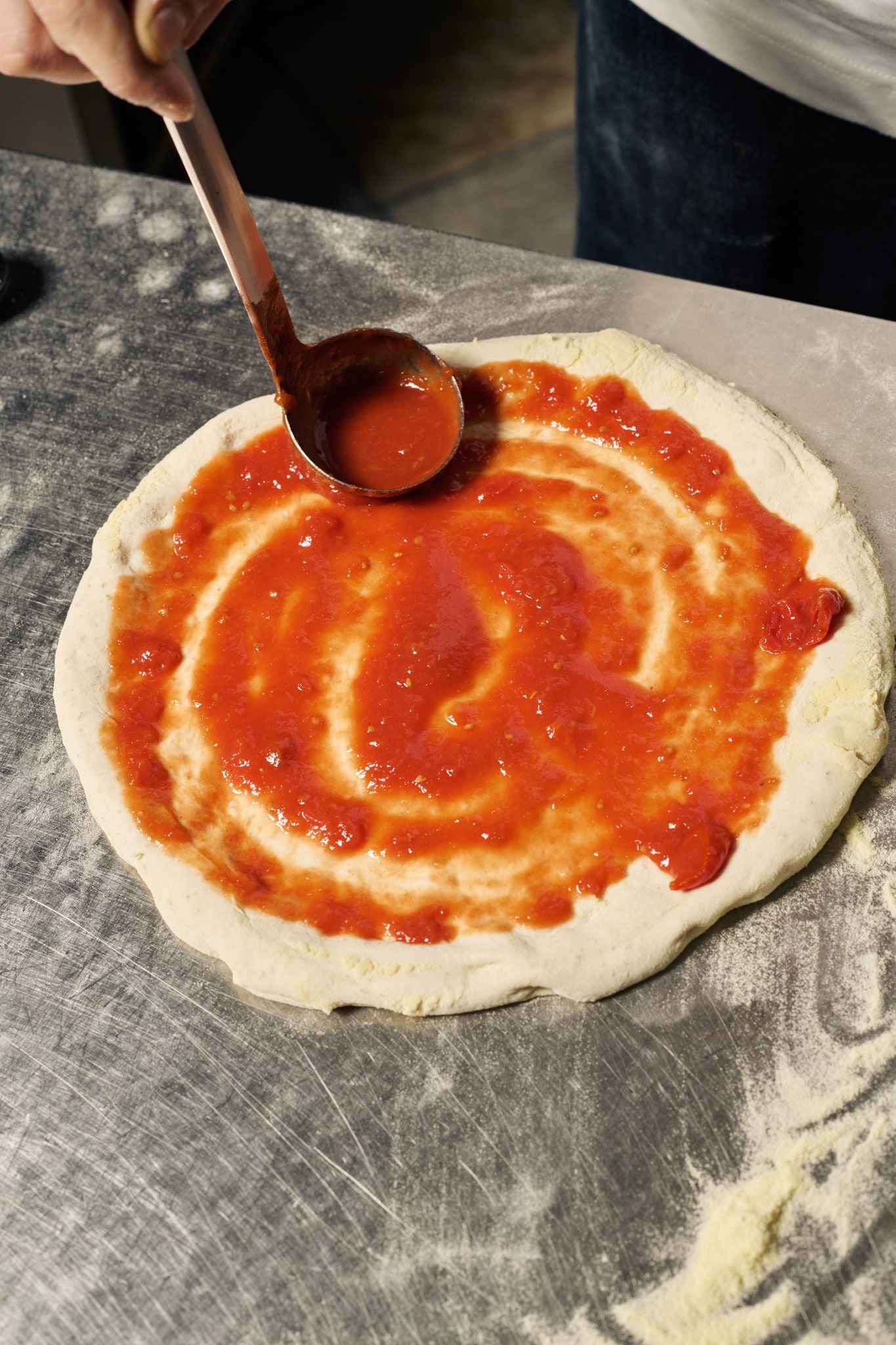 Il pomodoro steso a spirale sull’impasto con un mestolo