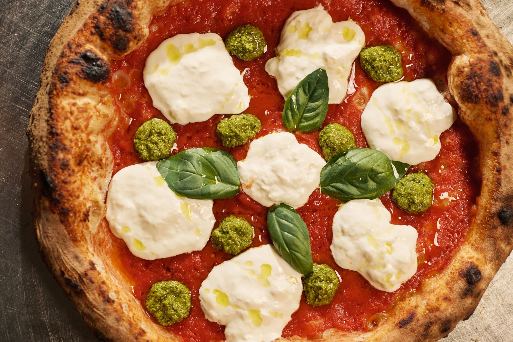 Pizza Spaccanapoli con stracciatella, pesto di basilico e foglie di basilico, vista dall’alto
