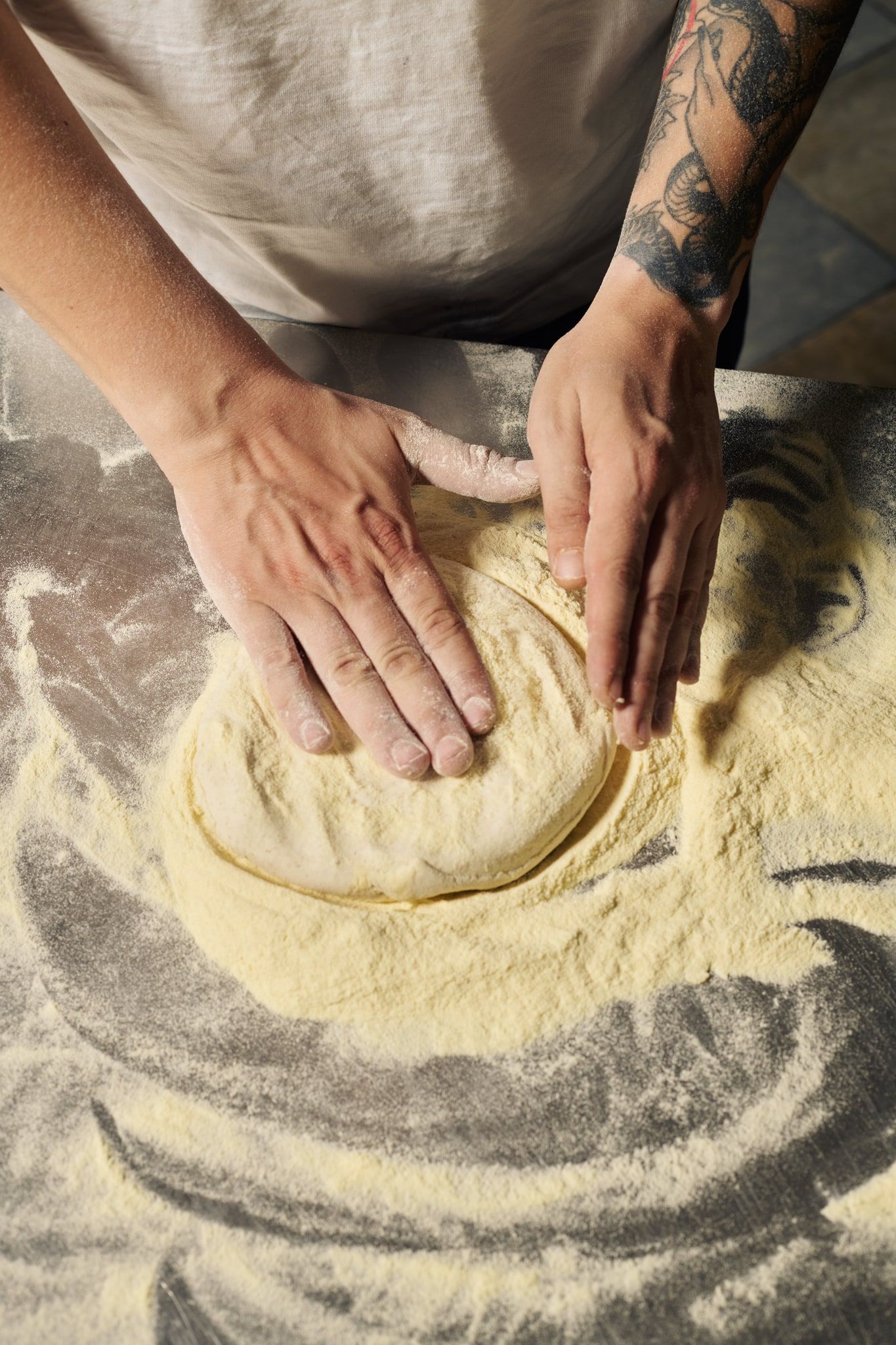 Mani che stendono l’impasto sulla semola